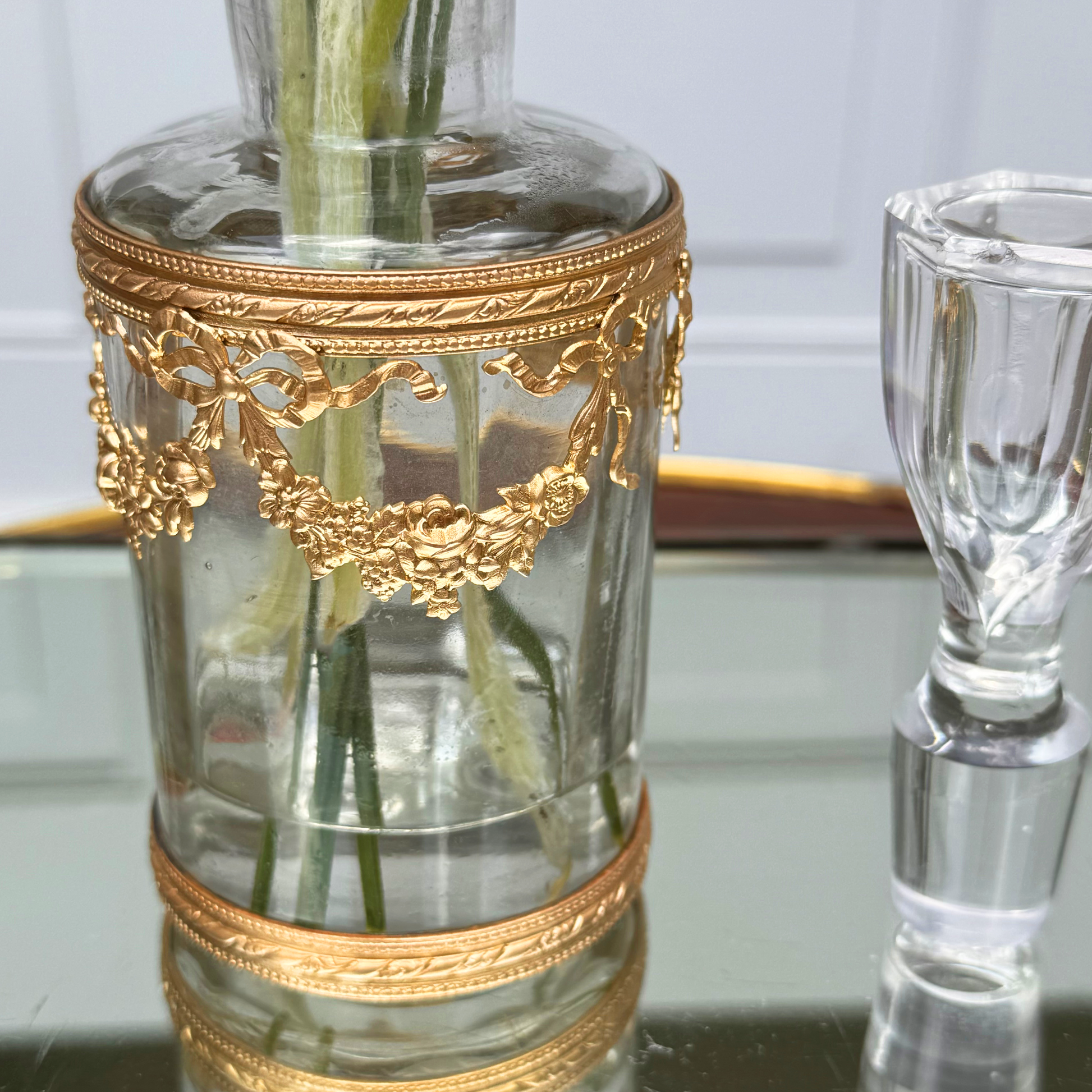 Close-up of the bottom section of the ormolu vessel and part of the crystal stopper, showing the chip to the top of the crystal stopper, on mirrored surface