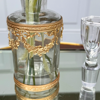 Close-up of the bottom section of the ormolu vessel and part of the crystal stopper, showing the chip to the top of the crystal stopper, on mirrored surface