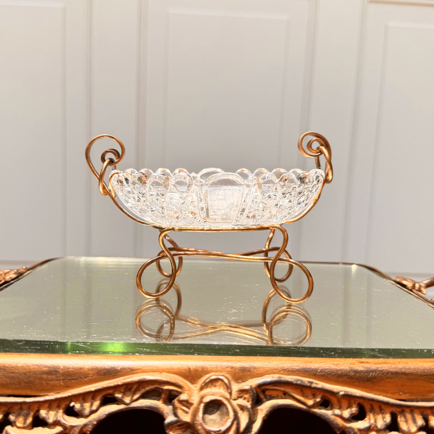 Antique Baccarat catchall, straight-on view from front at level showing brass spiral mounting detail and the crystal edge and details, placed on mirror surface