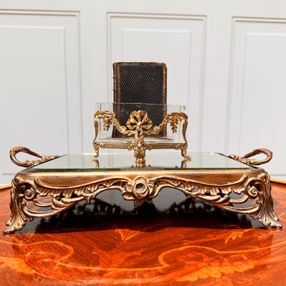 Antique mini brass-mounted crystal jardinière with diamond-shaped crystal insert, front straight-on view, placed on ornate footed mirrored riser. A small black leather book is placed inside the jardinière.