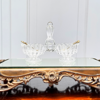 Antique Baccarat crystal double salt cellar with alternating frosted and unfrosted design, front view on mirrored surface, with two small gold colored spoons, one in each side
