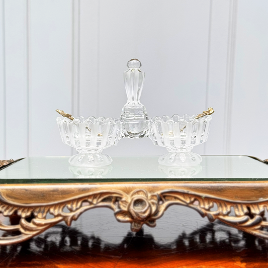 Antique Baccarat crystal double salt cellar with alternating frosted and unfrosted design, front view on mirrored surface, with two small gold colored spoons, one in each side