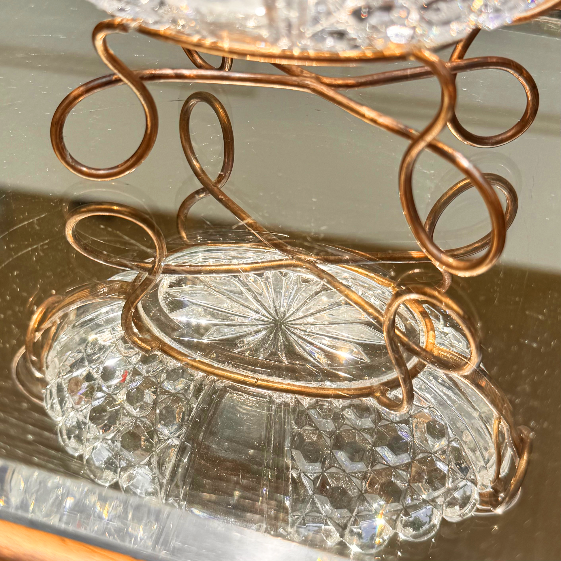 Antique Baccarat crystal catchall close up on the spiral brass wired mounting reflecting also the crystal bowl in the mirror surface it's placed on