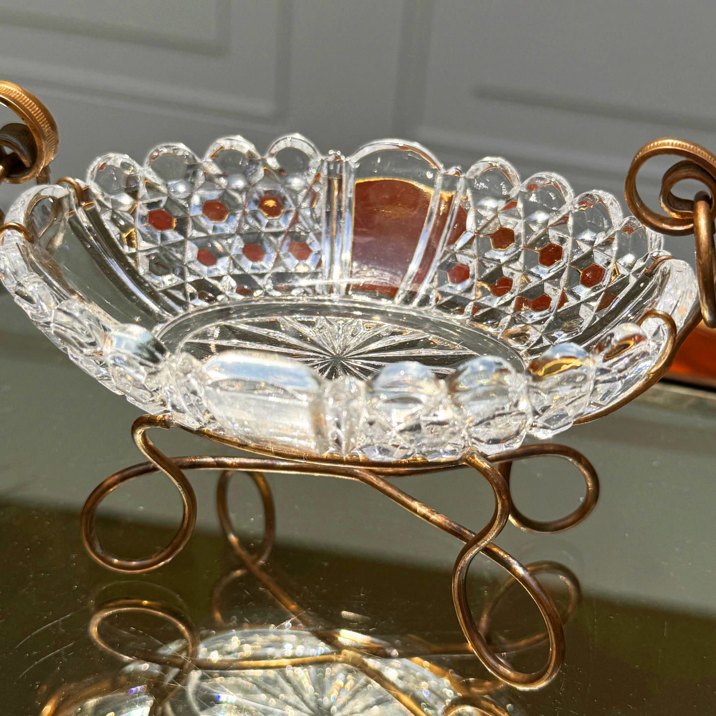 Antique Baccarat crystal catchall close up on the crystal bowl and mounting base, reflecting also in the mirrored surface it's placed on