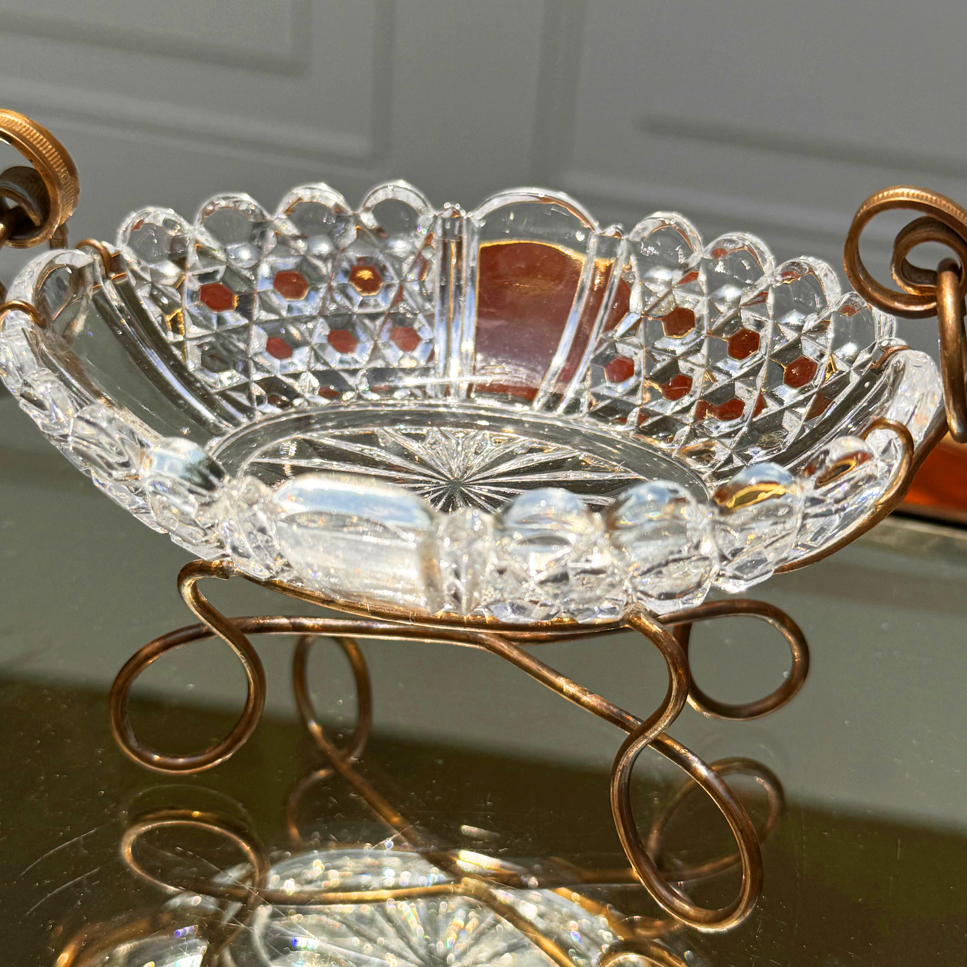 Antique Baccarat crystal catchall close up on the crystal bowl and mounting base, reflecting also in the mirrored surface it's placed on