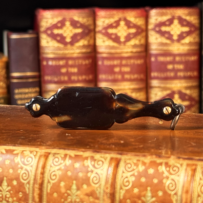 An antique folding lorgnette and spectacles shown folded with a tortoiseshell handle, silver colored frames,  resting on a leather book, backside shown