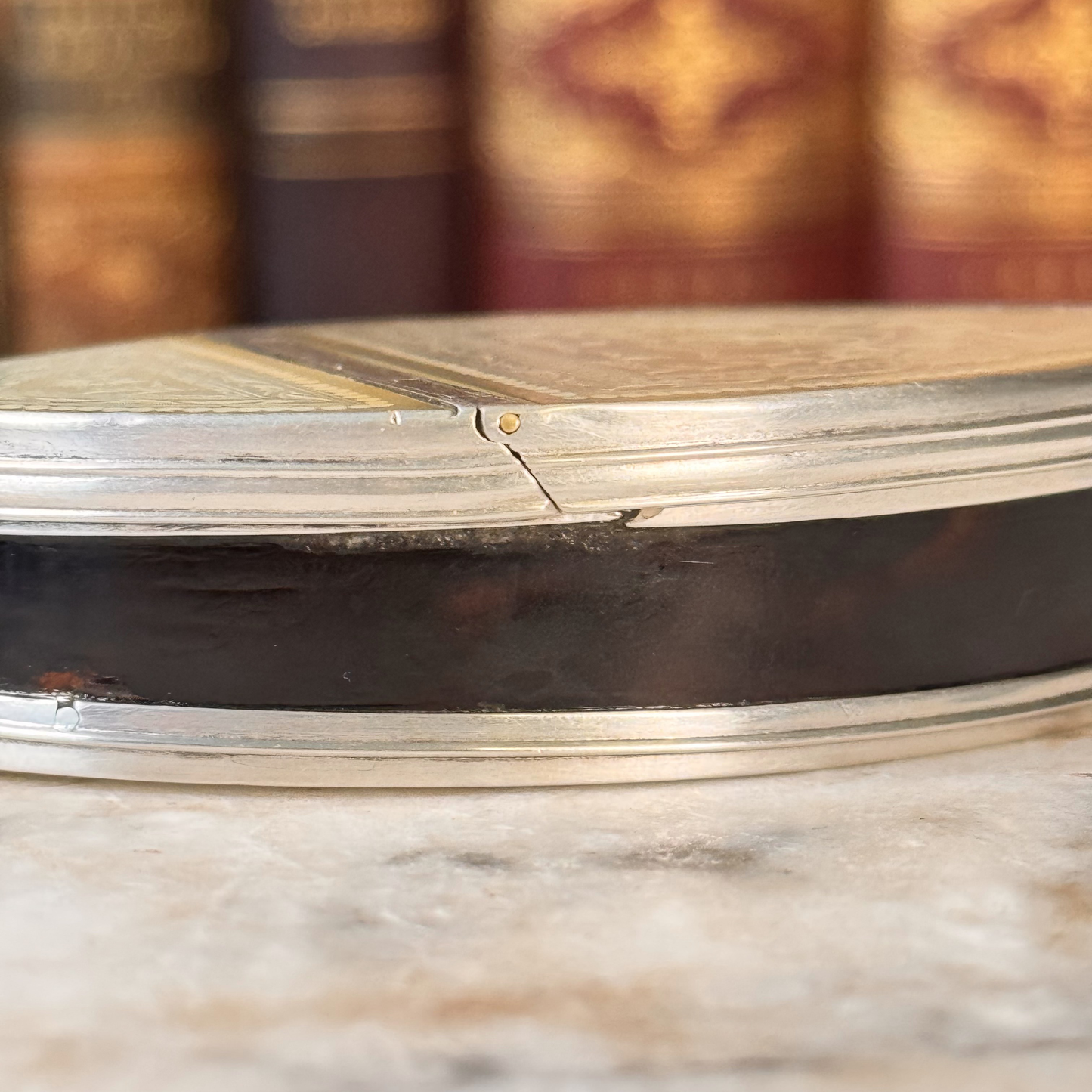 An antique oval tortoiseshell, mother-of-pearl, and silver snuff box, shown from the side highlighting the tortoiseshell and silver mounting and where it meets