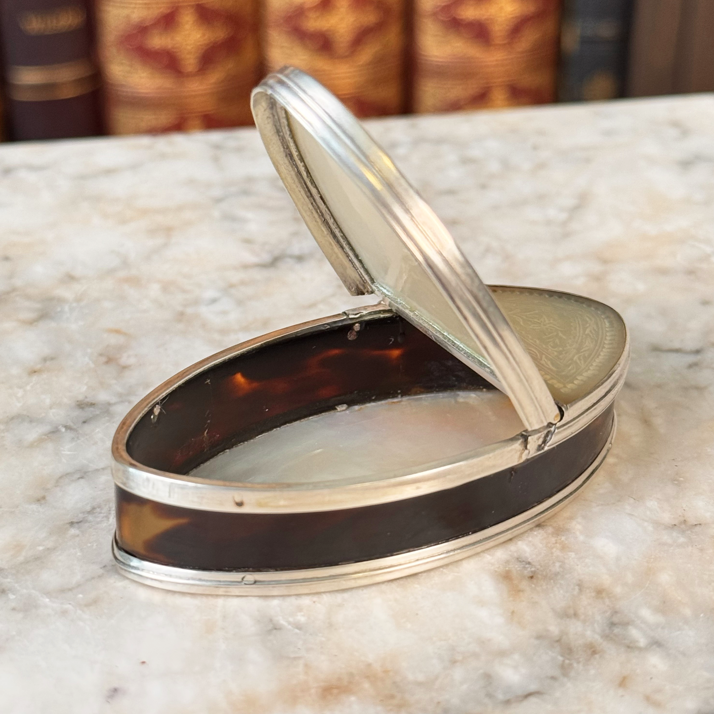 An antique oval tortoiseshell, mother-of-pearl, and silver snuff box, shown open highlighting the tortoiseshell inside