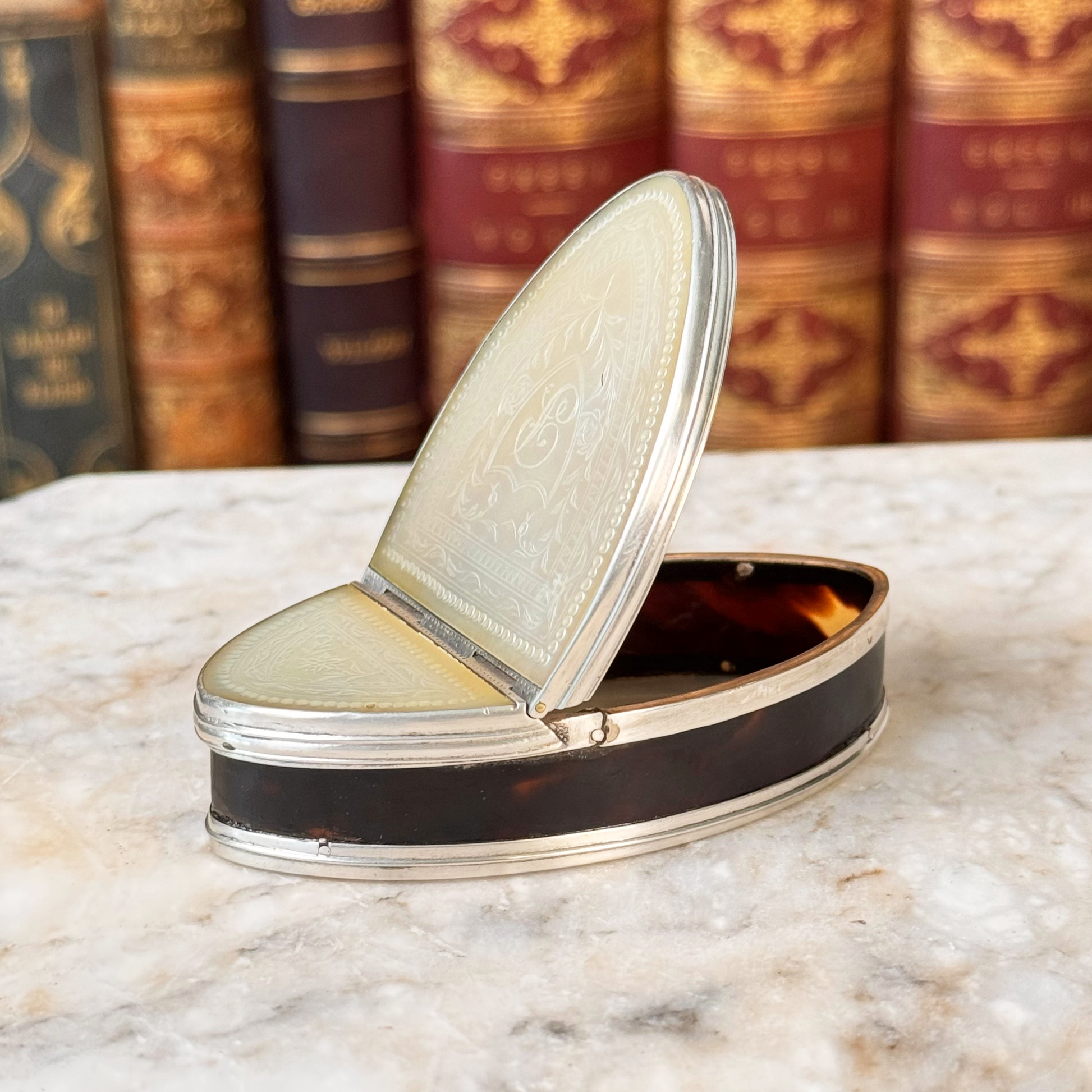 An antique oval tortoiseshell, mother-of-pearl, and silver snuff box, shown open