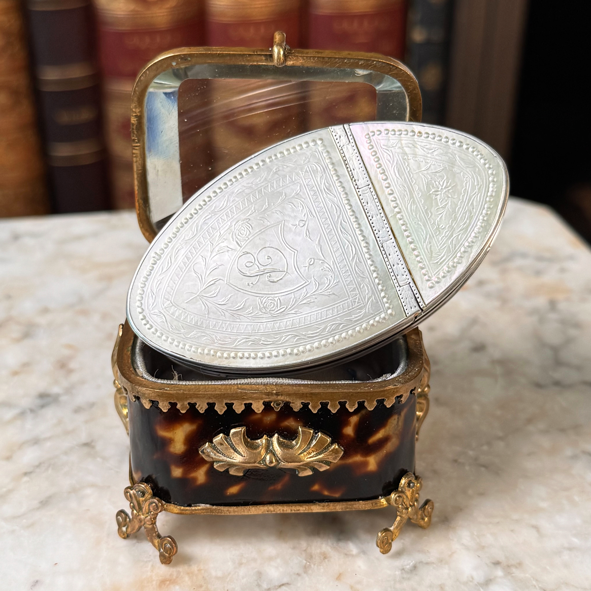 An antique oval tortoiseshell, mother-of-pearl, and silver snuff box, placed in a miniature jewelry box, close up of details on mother-of-pearl lid