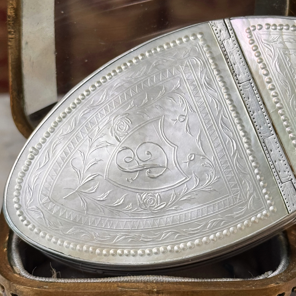 An antique oval tortoiseshell, mother-of-pearl, and silver snuff box, placed in a miniature jewelry box, close up of details on mother-of-pearl lid