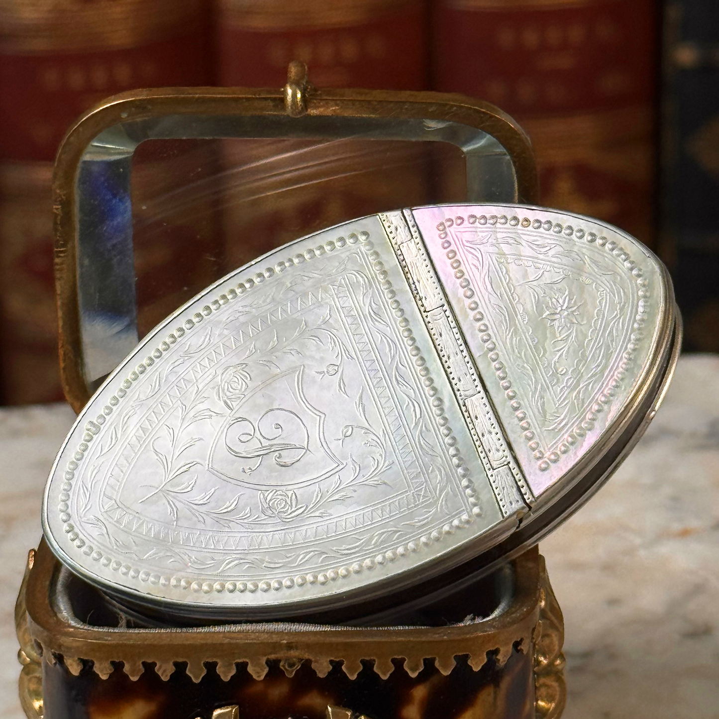 An antique oval tortoiseshell, mother-of-pearl, and silver snuff box, placed in a miniature jewelry box, close up of details on mother-of-pearl lid