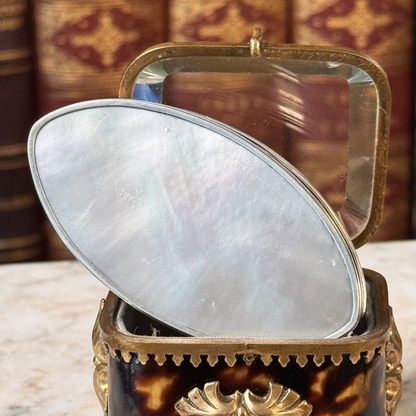 An antique oval tortoiseshell, mother-of-pearl, and silver snuff box, placed in a miniature jewelry box, close up of mother-of-pearl bottom