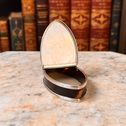 An antique oval tortoiseshell, mother-of-pearl, and silver snuff box, shown open highlighting the etched cross on the mother-of-pearl lid inside