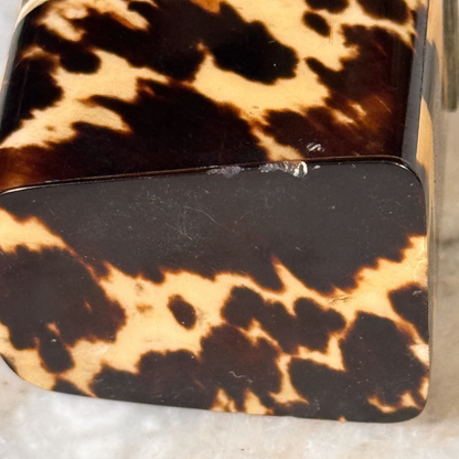 An antique tortoiseshell box with a glossy dark brown and amber pattern, shown from the bottom featuring some chipping to one edge
