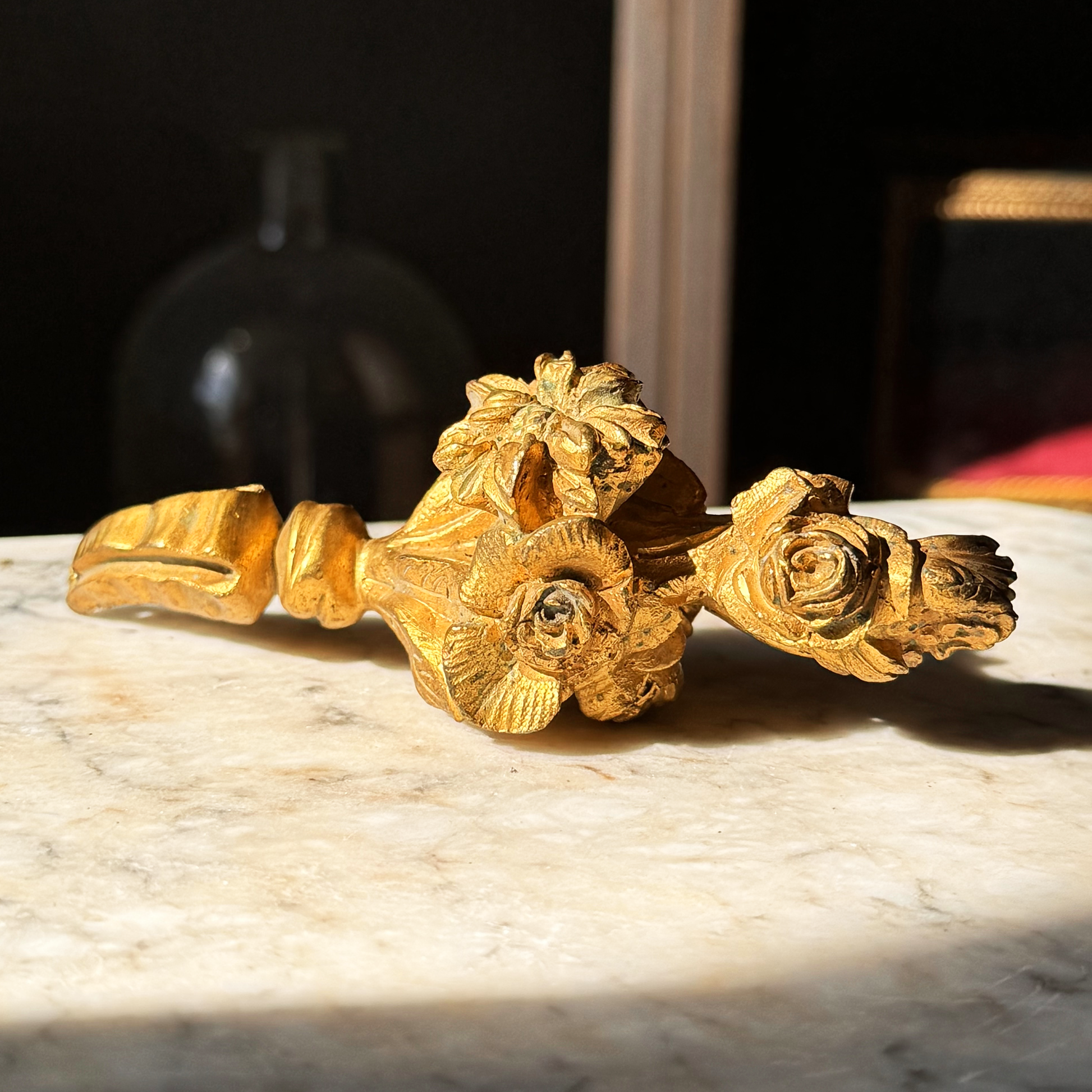 Decorative gold salvage piece with floral design on a marble surface