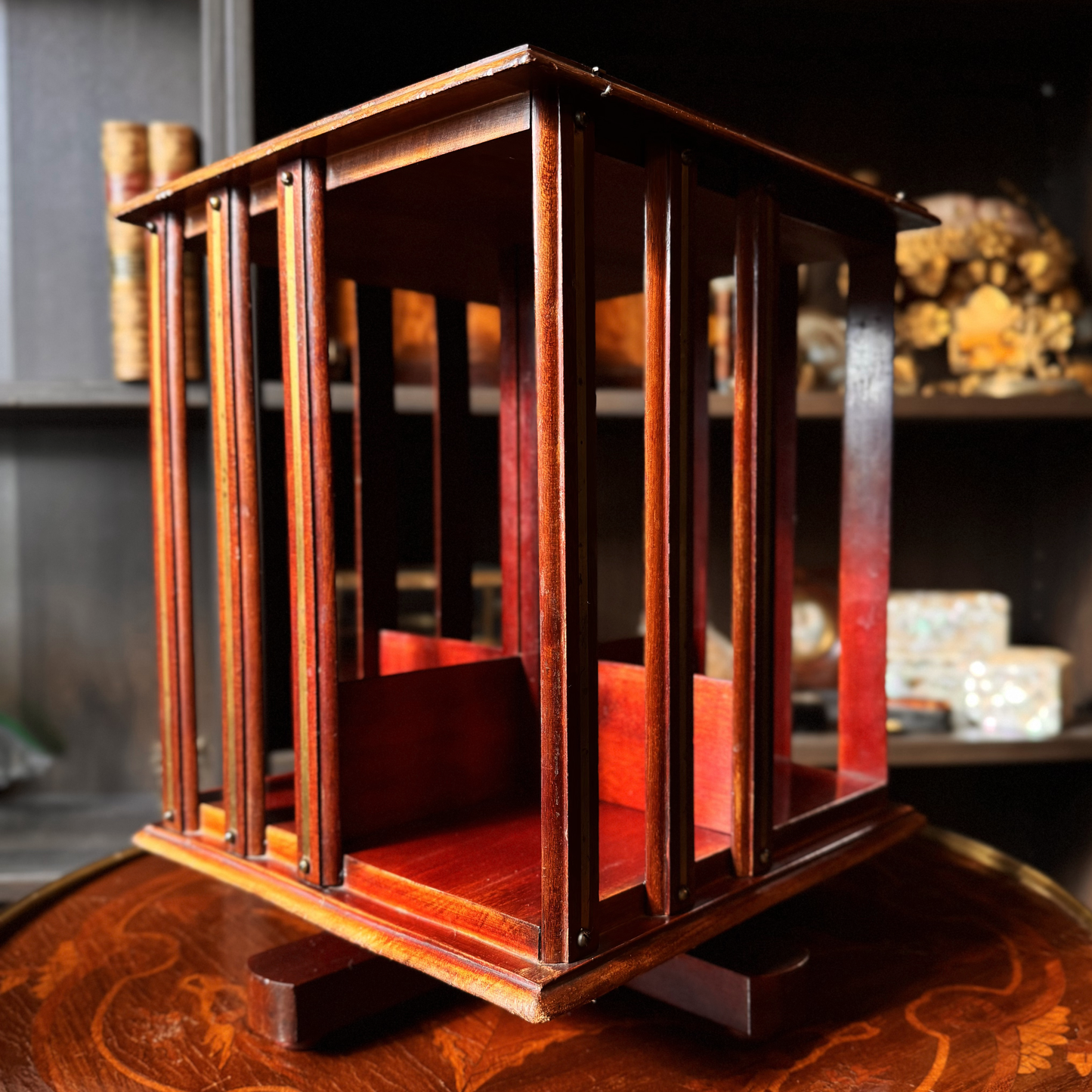 Wooden revolving bookshelf with brass inlay on a wooden surface