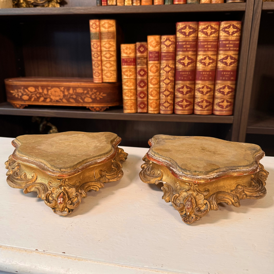 Pair of antique gilt wood and gesso risers on a bookshelf, different angle