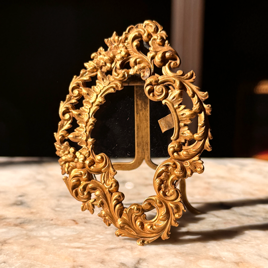 Decorative gold frame with intricate designs on a marble surface